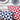 Two geometric-patterned pillows in red, white, and blue on a wooden surface.