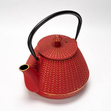 Red textured teapot with black handle on a white background