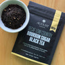 August Decaf Low Country Bourbon Sugar Black Tea package with a bowl of tea leaves on a wooden surface