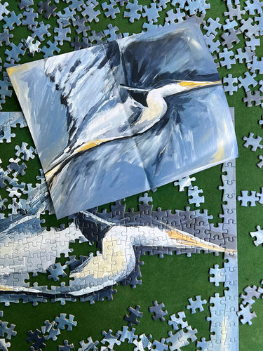 Jigsaw puzzle with a completed section featuring a bird painting on a green surface.