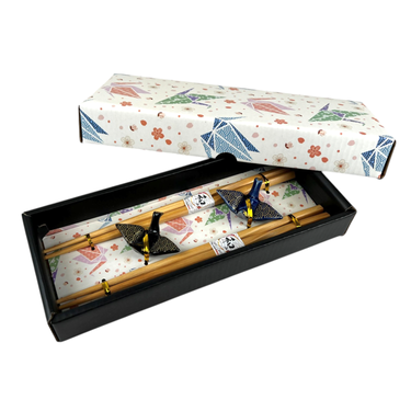 Set of wooden chopsticks with decorative ends in a patterned box on a white background