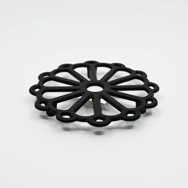 Black trivet with floral design on a white background