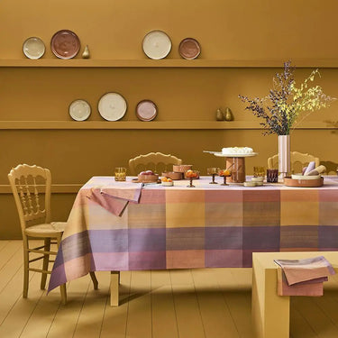 Dining room with a checkered tablecloth, chairs, and decorative plates on shelves.