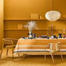 Dining room with a table set for a meal against a mustard yellow wall.