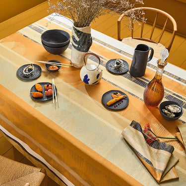 Dining table set with tea set, plates of food, and decorative items on a striped tablecloth.
