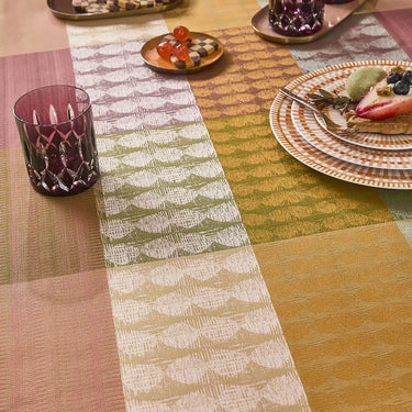Patterned table runner on a wooden table with plates and glasses.