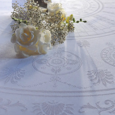 White roses and baby's breath on a patterned white fabric background