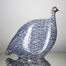 Ceramic bird figurine with blue and white pattern on a plain background