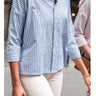 Person wearing a blue and white striped shirt with rolled-up sleeves.