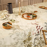 Dining table set with floral tablecloth, plates, and candles in a cozy indoor setting.