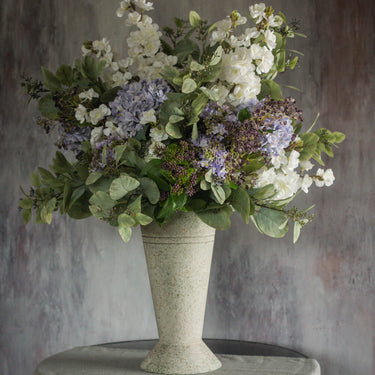 Floral arrangement in a textured vase against a textured wall