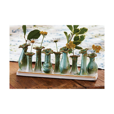 Set of small ceramic vases with plants on a wooden surface